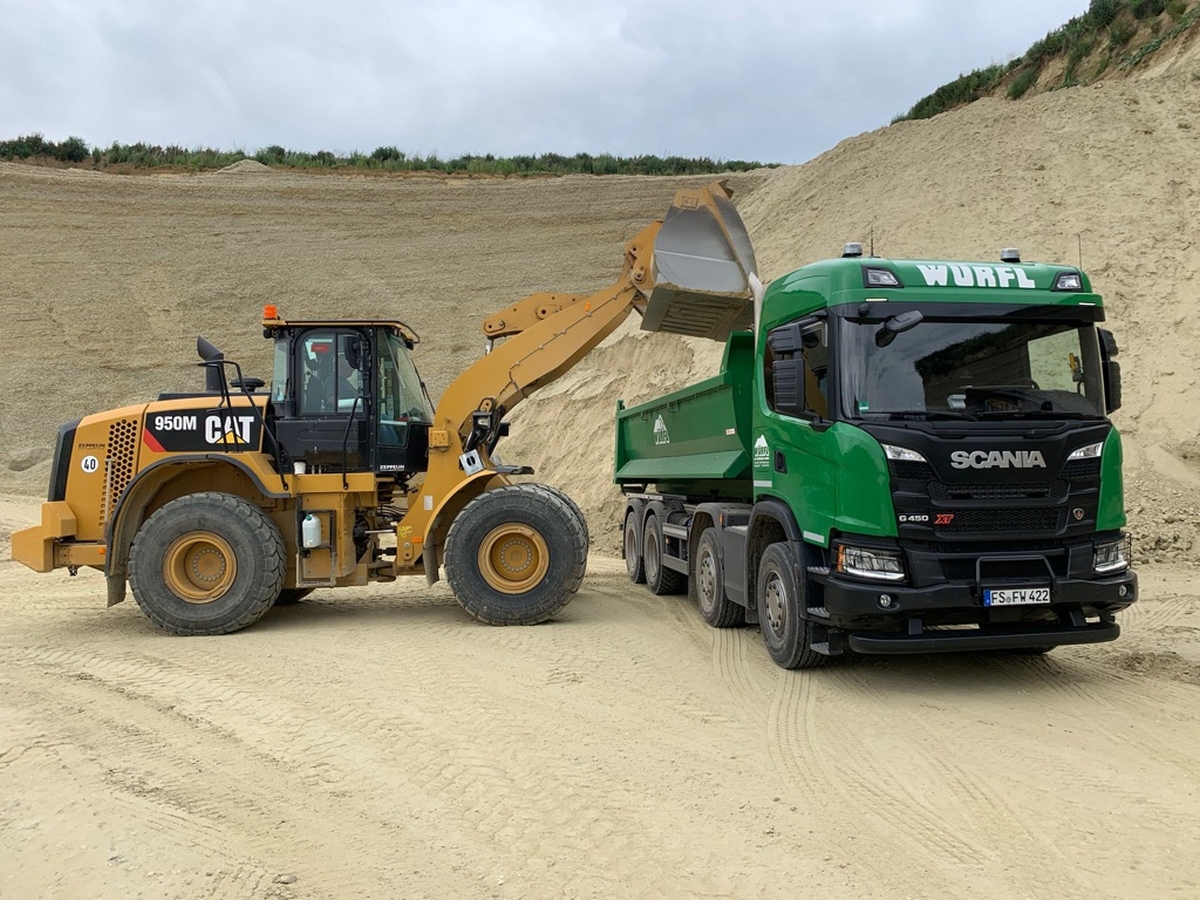 Beispielbild für Materiallieferung: Ein Radlader der Material in einen LKW kippt.